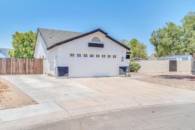 view of side of home with a garage, fence, concrete driveway, stucco siding, and a gate