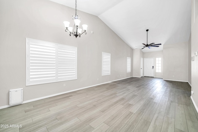 unfurnished living room featuring ceiling fan with notable chandelier, wood finished floors, baseboards, and high vaulted ceiling