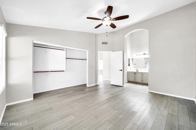 unfurnished bedroom featuring a closet, visible vents, wood finished floors, a sink, and baseboards