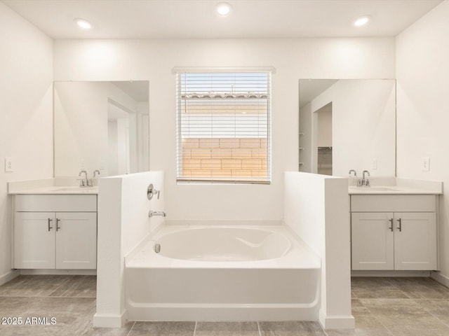 bathroom with a sink, a bath, and two vanities