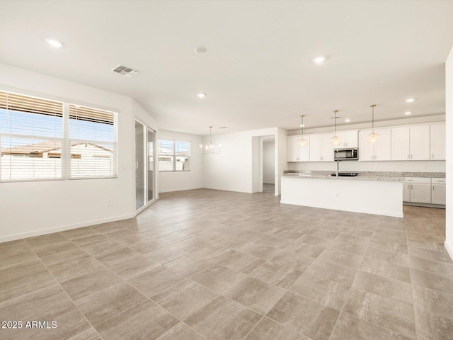 unfurnished living room featuring an inviting chandelier, recessed lighting, and visible vents