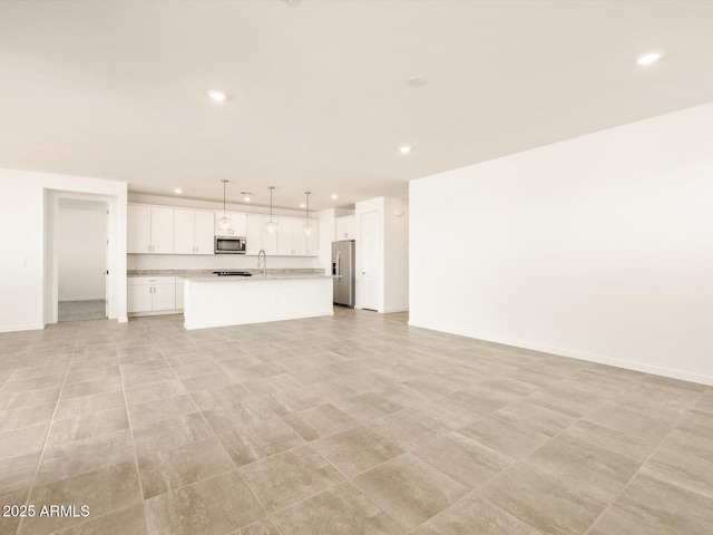 unfurnished living room featuring a sink, baseboards, and recessed lighting