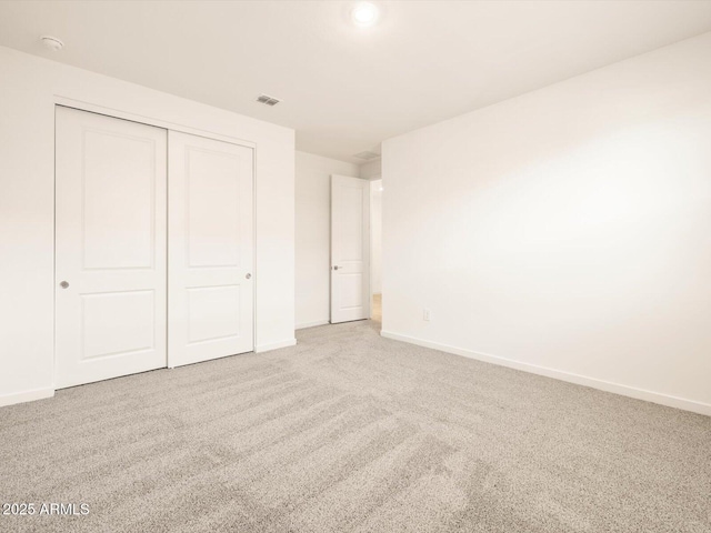 unfurnished bedroom with baseboards, visible vents, carpet, and a closet