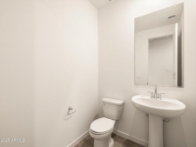 bathroom with baseboards, toilet, and visible vents