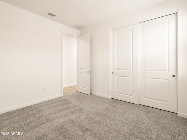 unfurnished bedroom with light colored carpet and a closet