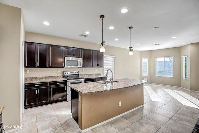 kitchen with sink, light stone counters, pendant lighting, a center island with sink, and appliances with stainless steel finishes