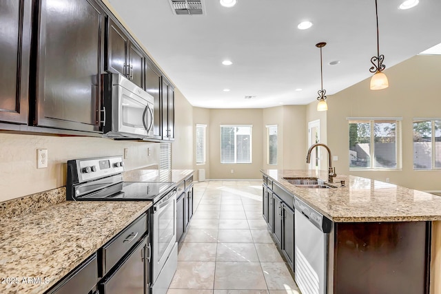 kitchen featuring light stone countertops, sink, hanging light fixtures, a kitchen island with sink, and appliances with stainless steel finishes