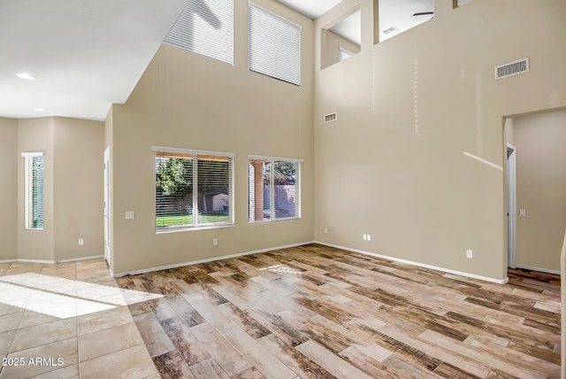 unfurnished living room with a high ceiling and light hardwood / wood-style floors