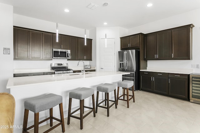 kitchen featuring visible vents, a breakfast bar, a sink, stainless steel appliances, and wine cooler