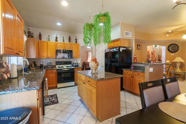 111 N Soho Pl, Chandler, AZ 85225 - kitchen with black appliances, a ceiling fan, arched walkways, dark stone countertops, and a kitchen island