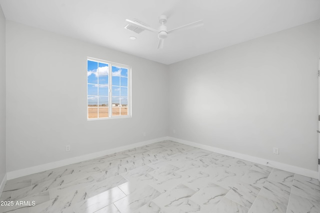 empty room with ceiling fan, marble finish floor, and baseboards