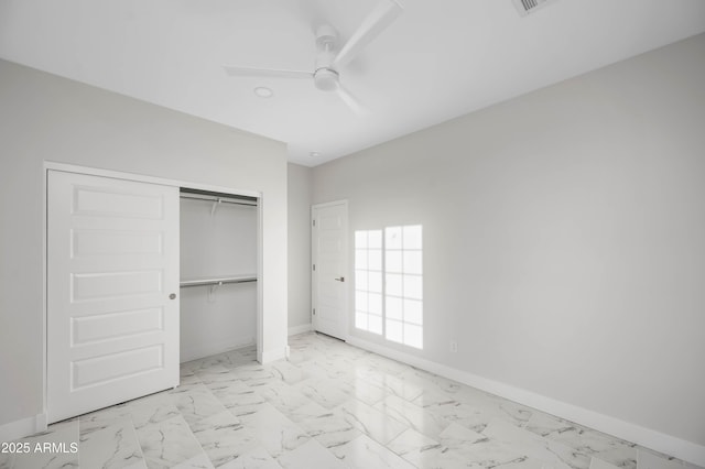 unfurnished bedroom featuring marble finish floor, a ceiling fan, baseboards, and a closet