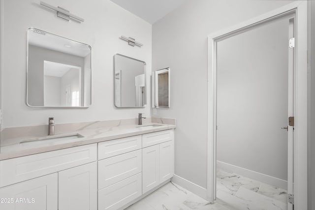 bathroom featuring marble finish floor, double vanity, a sink, and baseboards