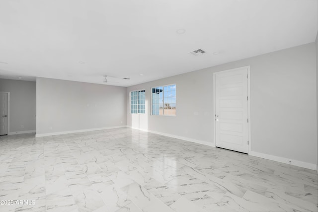 unfurnished room with a ceiling fan, marble finish floor, visible vents, and baseboards