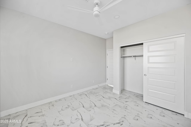 unfurnished bedroom with marble finish floor, a closet, a ceiling fan, and baseboards