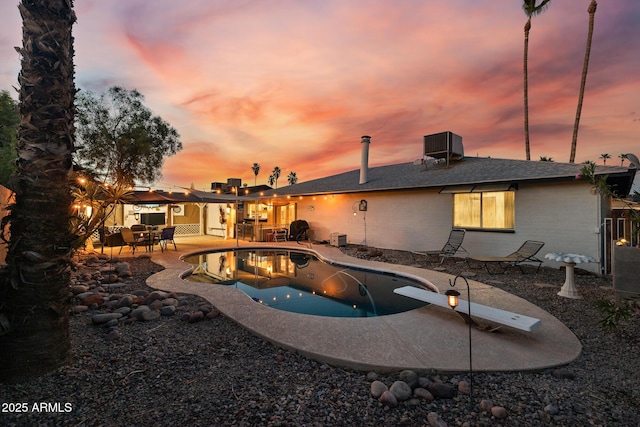 2062 S Emerson, Mesa, AZ 85210 - pool at dusk featuring a patio, an outdoor pool, a diving board, and outdoor dining space