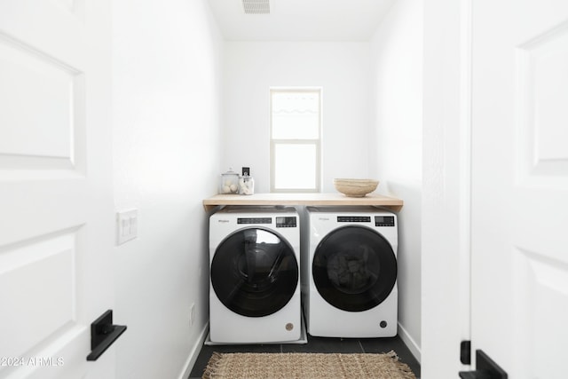 laundry room with washing machine and dryer and dark tile patterned flooring