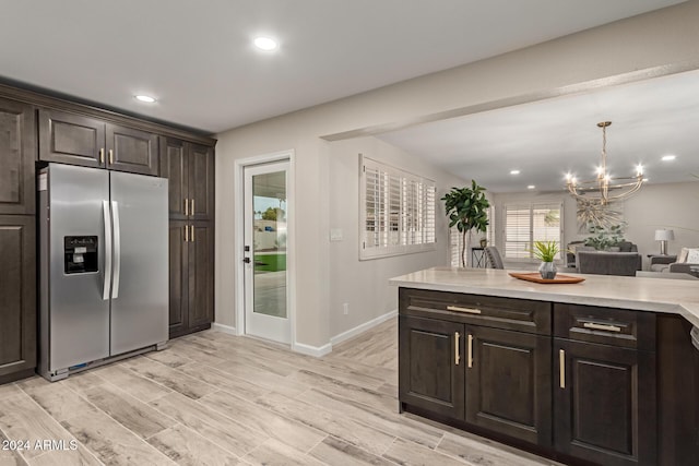 kitchen with pendant lighting, stainless steel fridge, light wood-type flooring, dark brown cabinetry, and a chandelier