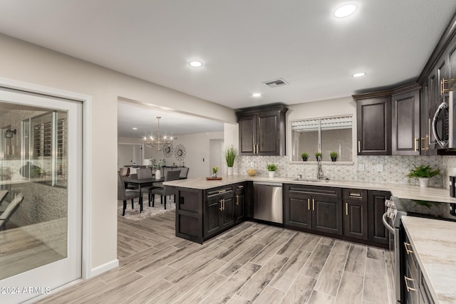 kitchen featuring dark brown cabinets, hanging light fixtures, appliances with stainless steel finishes, and light hardwood / wood-style flooring