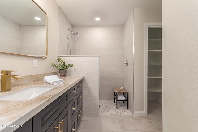 bathroom with a tile shower, vanity, and tile patterned floors