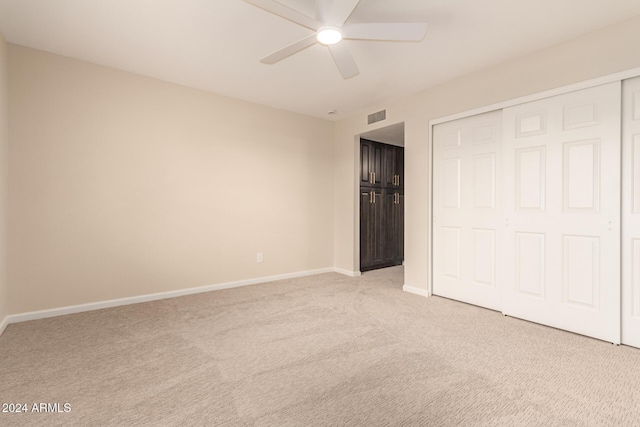 unfurnished bedroom featuring ceiling fan, light colored carpet, and a closet