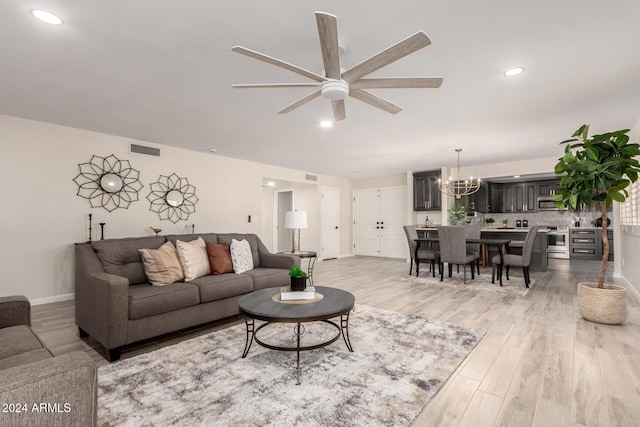 living room with ceiling fan with notable chandelier and light wood-type flooring