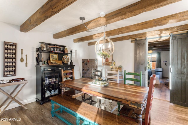 dining space with beamed ceiling, a barn door, and hardwood / wood-style flooring