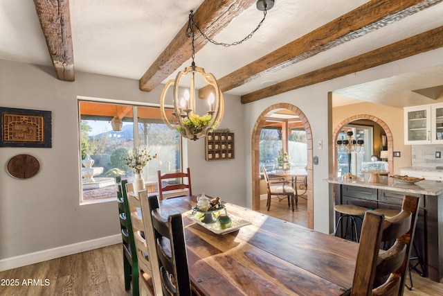 dining area with beamed ceiling, a chandelier, light hardwood / wood-style flooring, and a wealth of natural light