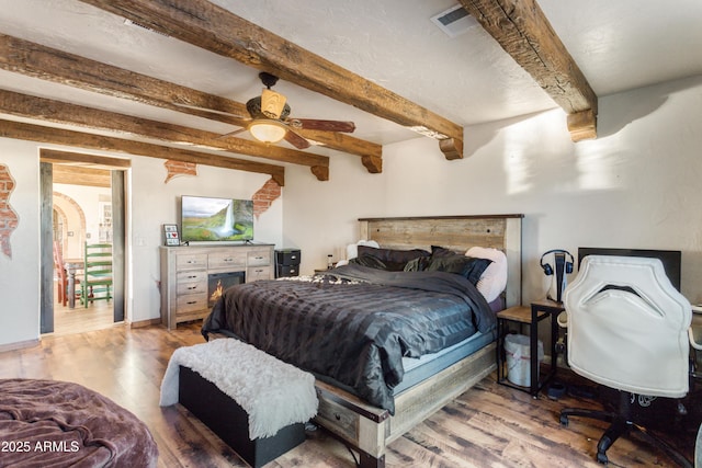 bedroom featuring hardwood / wood-style floors, ceiling fan, and beamed ceiling