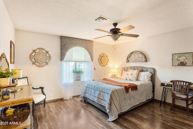 bedroom with ceiling fan, dark wood-type flooring, and a textured ceiling