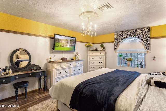 bedroom with a chandelier, a textured ceiling, and dark wood-type flooring