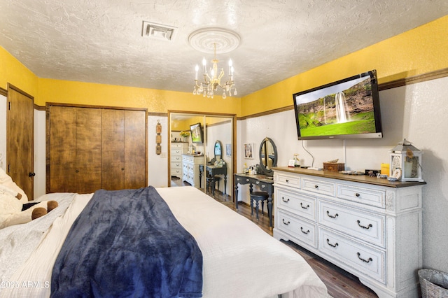 bedroom featuring a textured ceiling, two closets, a chandelier, and dark hardwood / wood-style floors