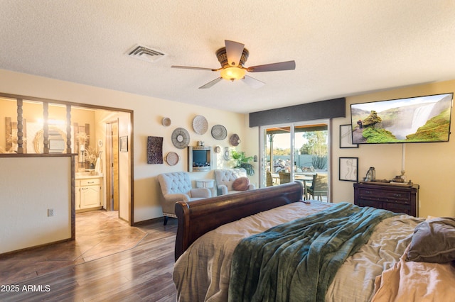 bedroom featuring hardwood / wood-style floors, access to outside, ensuite bath, ceiling fan, and a textured ceiling