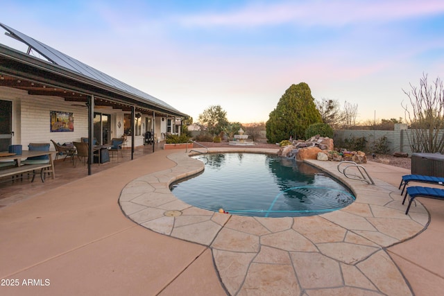 pool at dusk featuring a patio and pool water feature