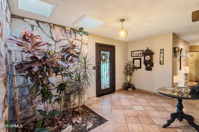 foyer with a textured ceiling, a skylight, and light tile patterned flooring