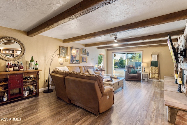 living room with hardwood / wood-style floors, a textured ceiling, beamed ceiling, and bar area