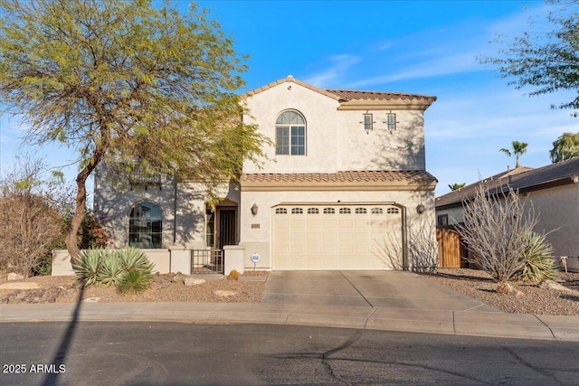 mediterranean / spanish home featuring concrete driveway, fence, a tile roof, and stucco siding