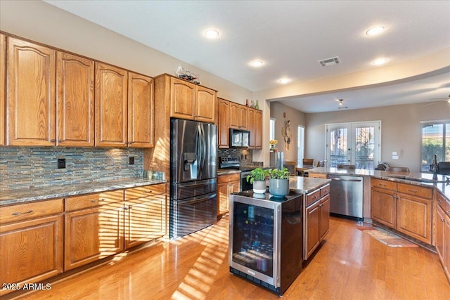 kitchen featuring wine cooler, a sink, visible vents, appliances with stainless steel finishes, and a center island