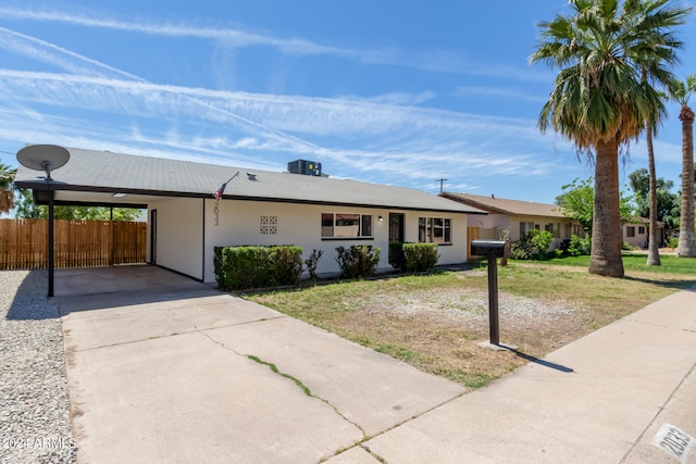 ranch-style home with a carport, a front lawn, and central air condition unit