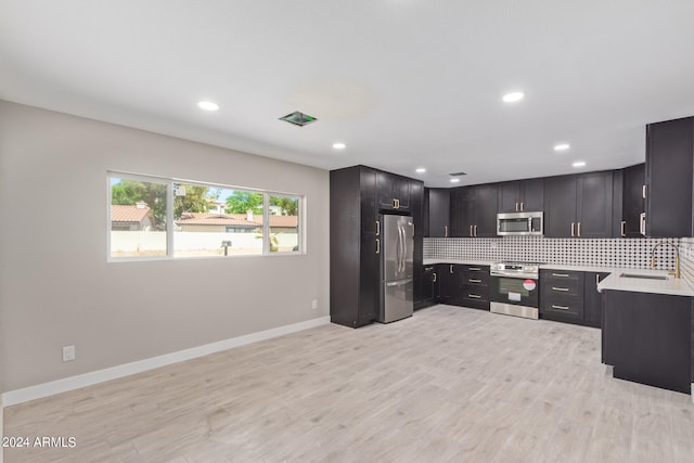 kitchen featuring sink, appliances with stainless steel finishes, backsplash, dark brown cabinetry, and light wood-type flooring