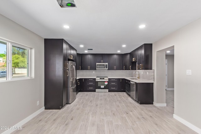 kitchen featuring sink, backsplash, light hardwood / wood-style floors, dark brown cabinetry, and stainless steel appliances