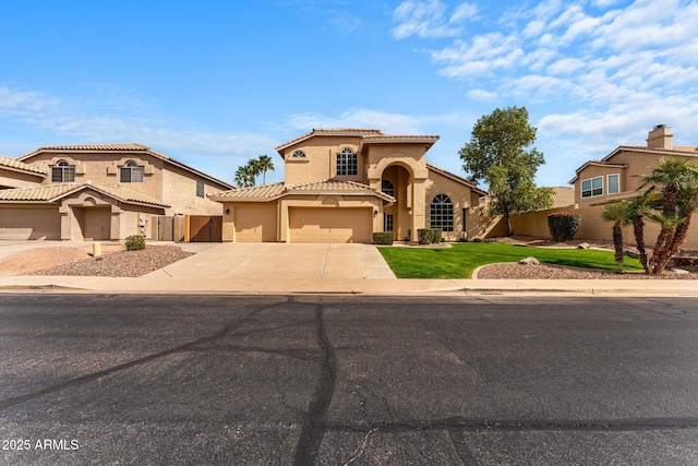mediterranean / spanish home with a tiled roof, stucco siding, a front yard, fence, and concrete driveway
