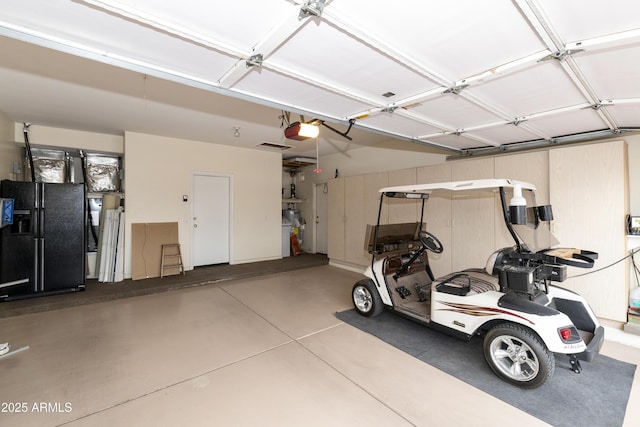 garage with a garage door opener and black refrigerator with ice dispenser