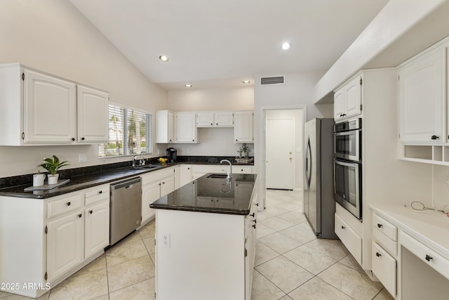 kitchen featuring appliances with stainless steel finishes, white cabinetry, and a kitchen island with sink