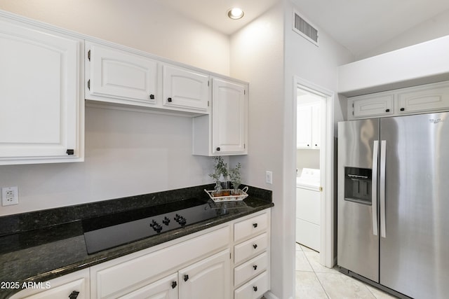 kitchen featuring white cabinets, stainless steel refrigerator with ice dispenser, dark stone countertops, light tile patterned flooring, and washer / clothes dryer