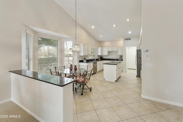 kitchen with kitchen peninsula, appliances with stainless steel finishes, high vaulted ceiling, and white cabinetry