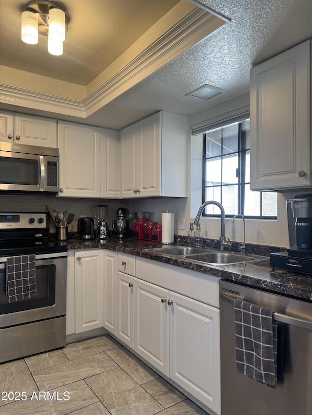 kitchen with crown molding, appliances with stainless steel finishes, white cabinets, a textured ceiling, and a sink