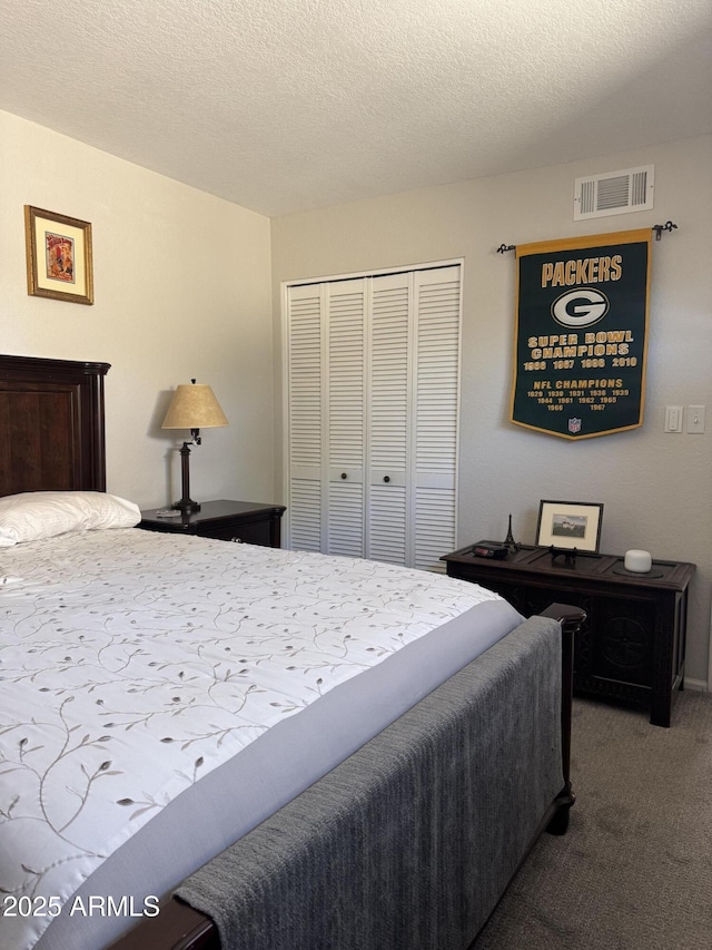 bedroom with carpet flooring, visible vents, a closet, and a textured ceiling