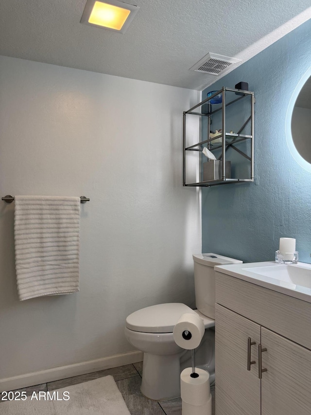 bathroom featuring visible vents, toilet, a textured ceiling, baseboards, and vanity