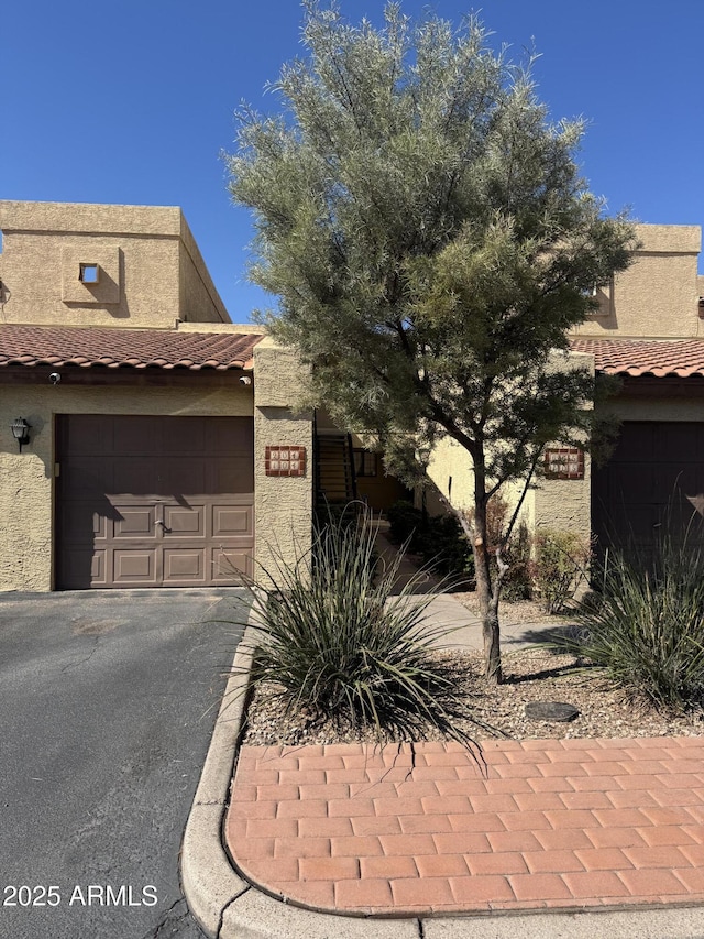 view of front of home featuring stucco siding, an attached garage, driveway, and a tile roof